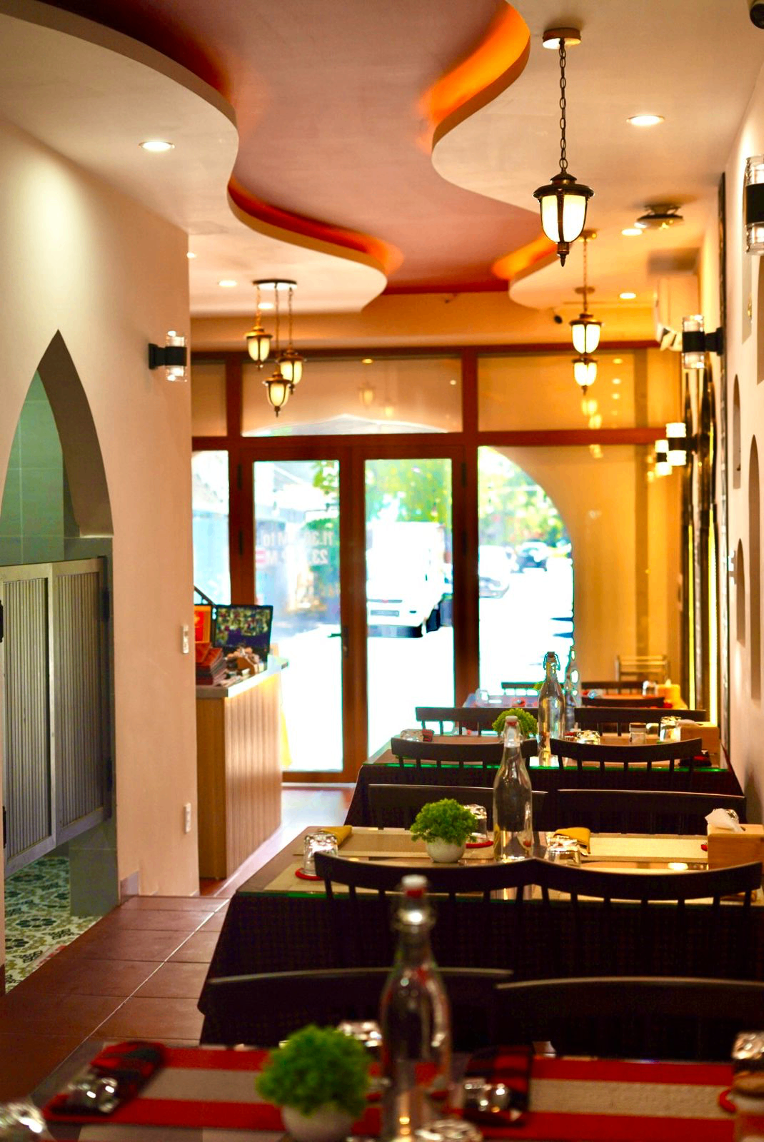Warm interior of Indian Aroma Restaurant in Da Nang with red ceiling details and pendant lamps